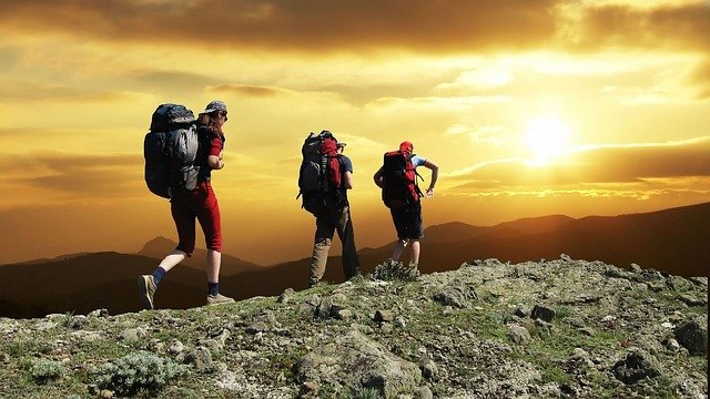 hikers at sunset carrying backpacks at capacity