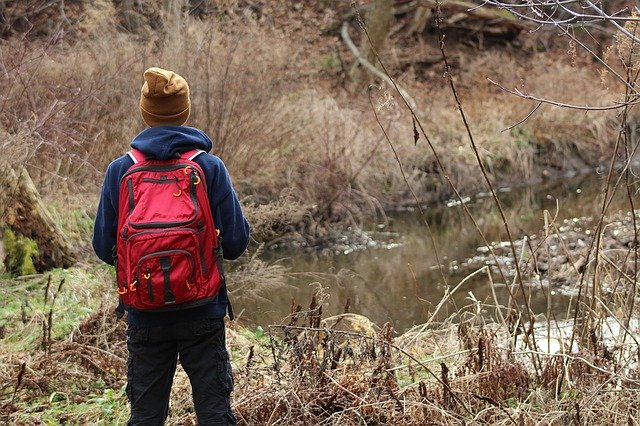 backpacker hiking next to river 